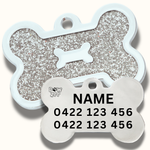 Dog tag shaped like a bone with glittery texture and engraved text on a white background